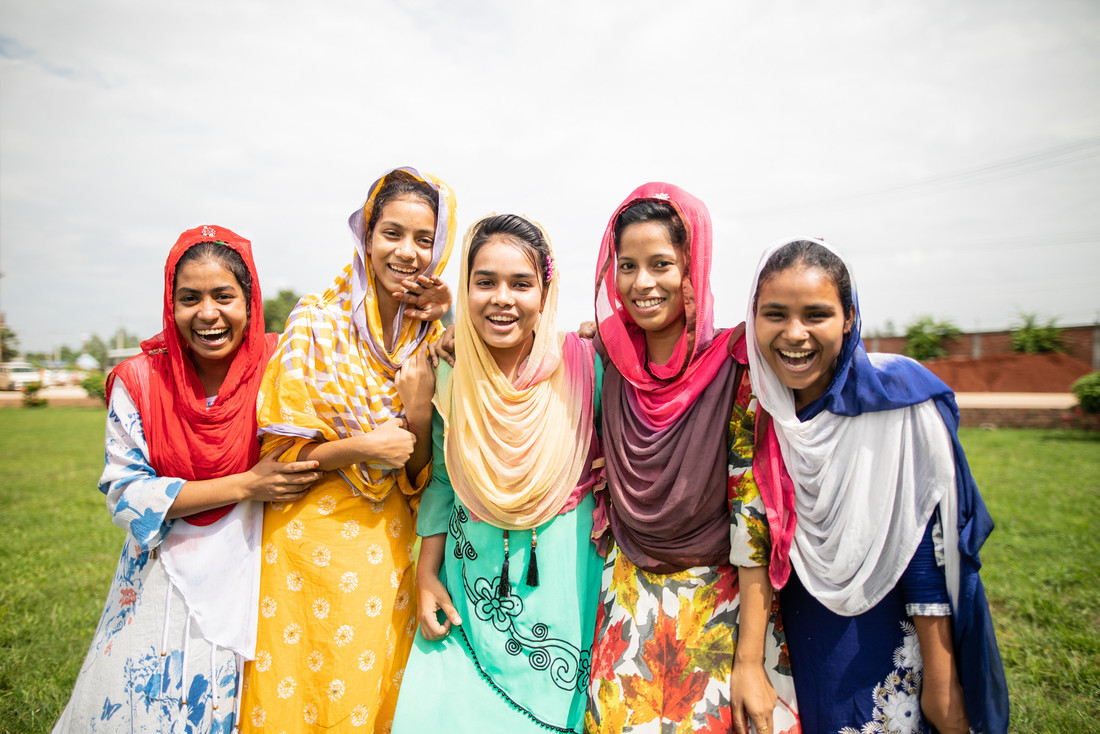 A group of young girls smile and laugh together.